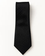 Cravate Matignon à plat : jacquard noir à petits carreaux gris disposés en diagonale.