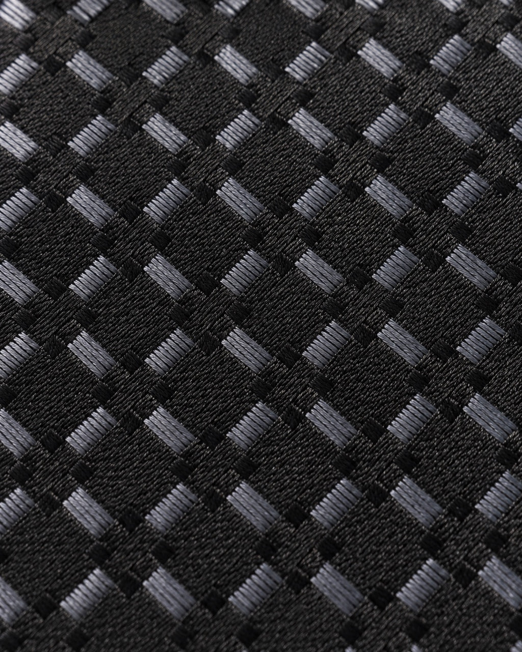 Gros plan du jacquard de soie Matignon : trame noire et petits carreaux gris aux reflets argentés.