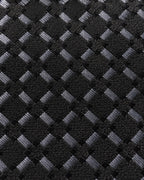 Gros plan du jacquard de soie Matignon : trame noire et petits carreaux gris aux reflets argentés.