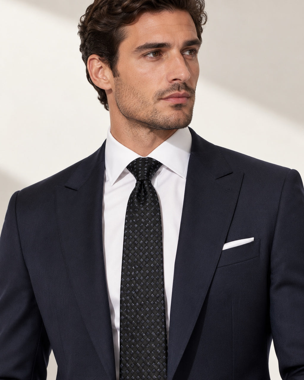 Cravate Matignon noire à petits motifs gris, portée avec un costume bleu marine et une chemise blanche.