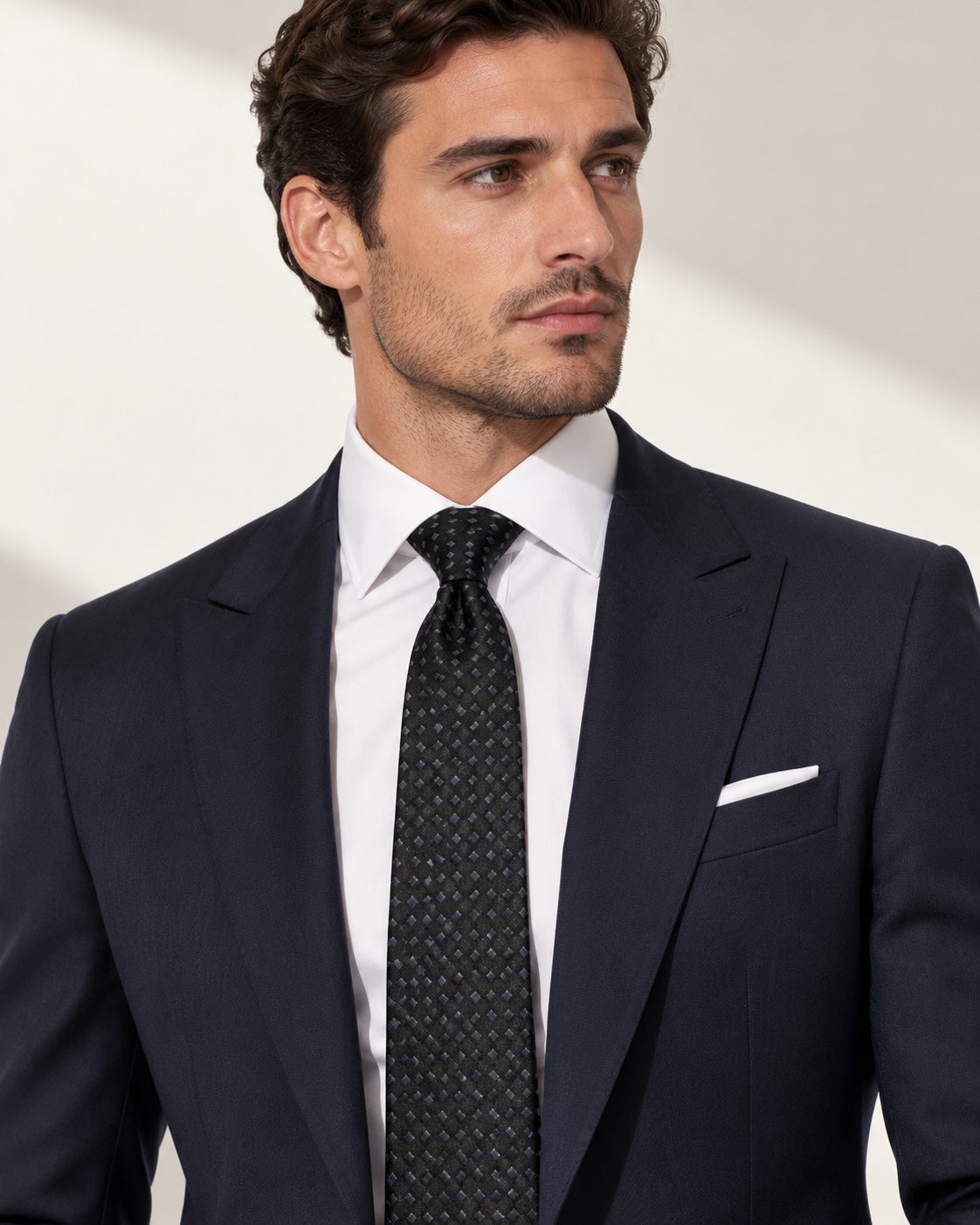 Cravate Matignon noire à petits motifs gris, portée avec un costume bleu marine et une chemise blanche.