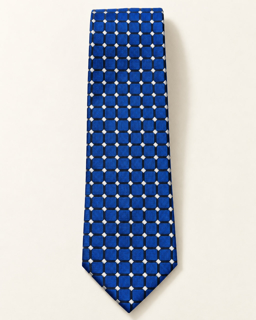 Cravate Penthièvre en soie présentée à plat, carreaux bleu royal soulignés d’une grille sombre et de petits losanges ivoire.