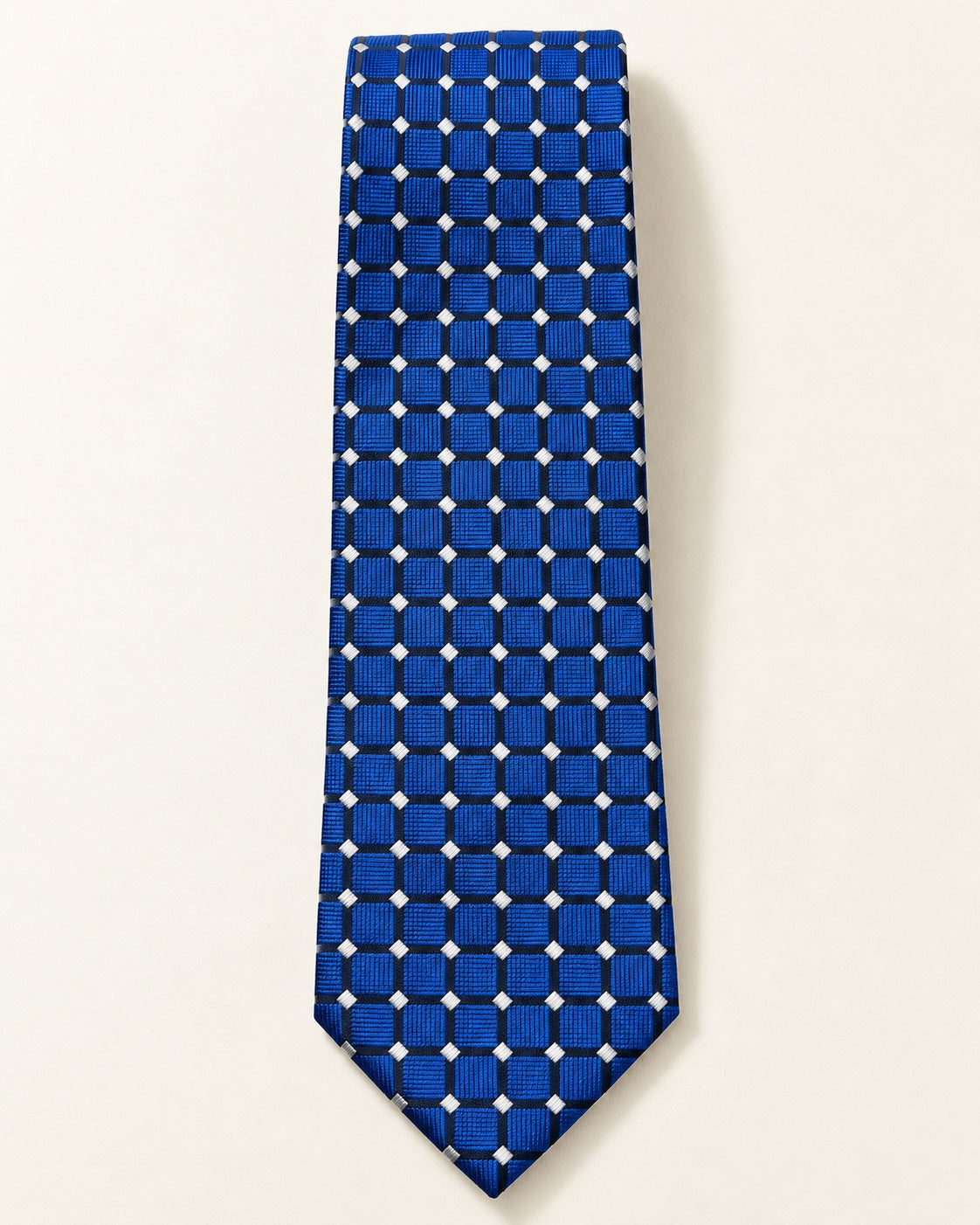 Cravate Penthièvre en soie présentée à plat, carreaux bleu royal soulignés d’une grille sombre et de petits losanges ivoire.