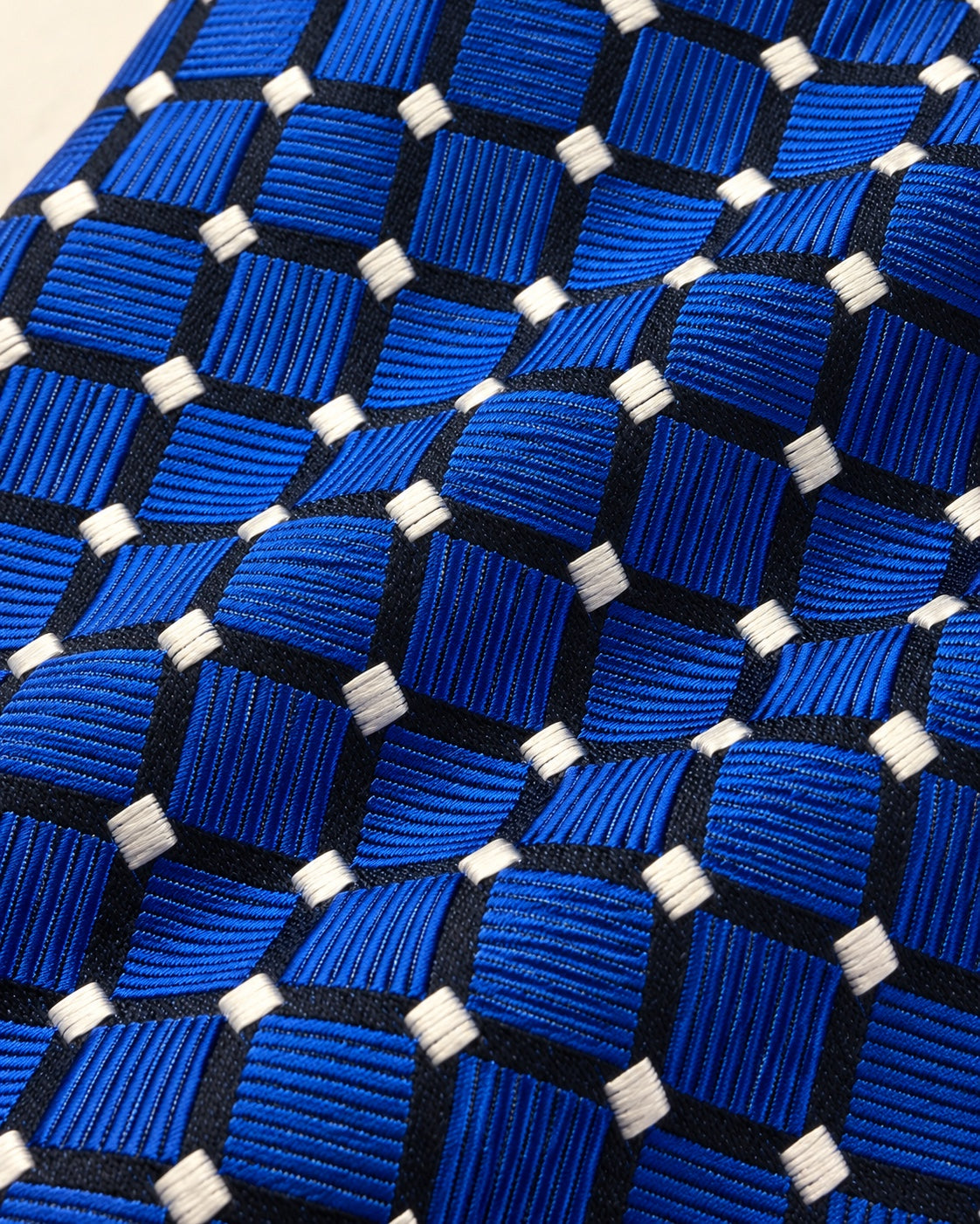 Détail du jacquard Penthièvre : carreaux bleu royal côtelés dans des directions alternées et petits motifs ivoire aux intersections.