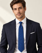 Cravate Penthièvre bleu royal à carreaux et petits losanges ivoire, portée avec une chemise blanche et un costume bleu marine.