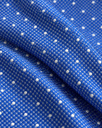 Gros plan du jacquard de soie Scribe : tissage bleu à petits motifs clairs et pois blancs en relief.