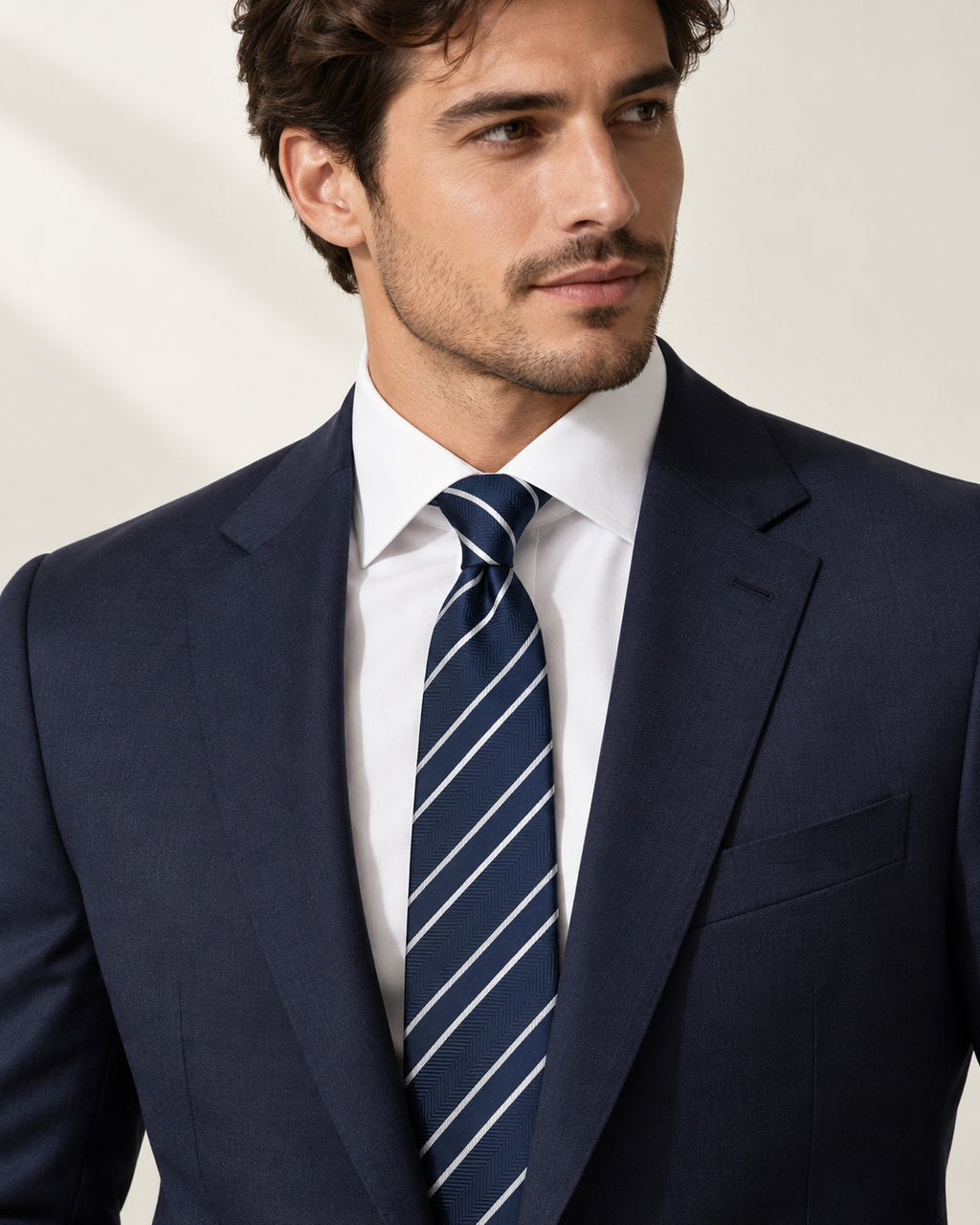 Cravate Tocqueville bleu marine à rayures blanches et chevrons, portée avec un costume marine