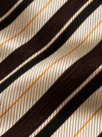 Gros plan du jacquard de soie Tronchet : rayures diagonales ivoire, brun chocolat et noir, avec de fins filets dorés.