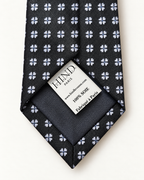 Dos de la cravate Valois noire à fleurettes, doublure sombre et étiquette Hind Kroussa Paris indiquant 100 % soie.