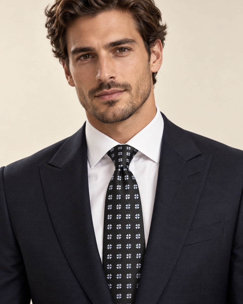 Cravate Valois noire à fleurettes bleu pâle, portée avec un costume sombre et une chemise blanche.