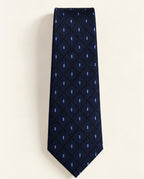 Cravate Vignon à plat, en jacquard de soie bleu marine à losanges noirs ponctués de petits motifs bleu ciel.