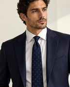 Cravate Vignon bleu marine à losanges et motifs bleu ciel, portée avec un costume marine et une chemise blanche.