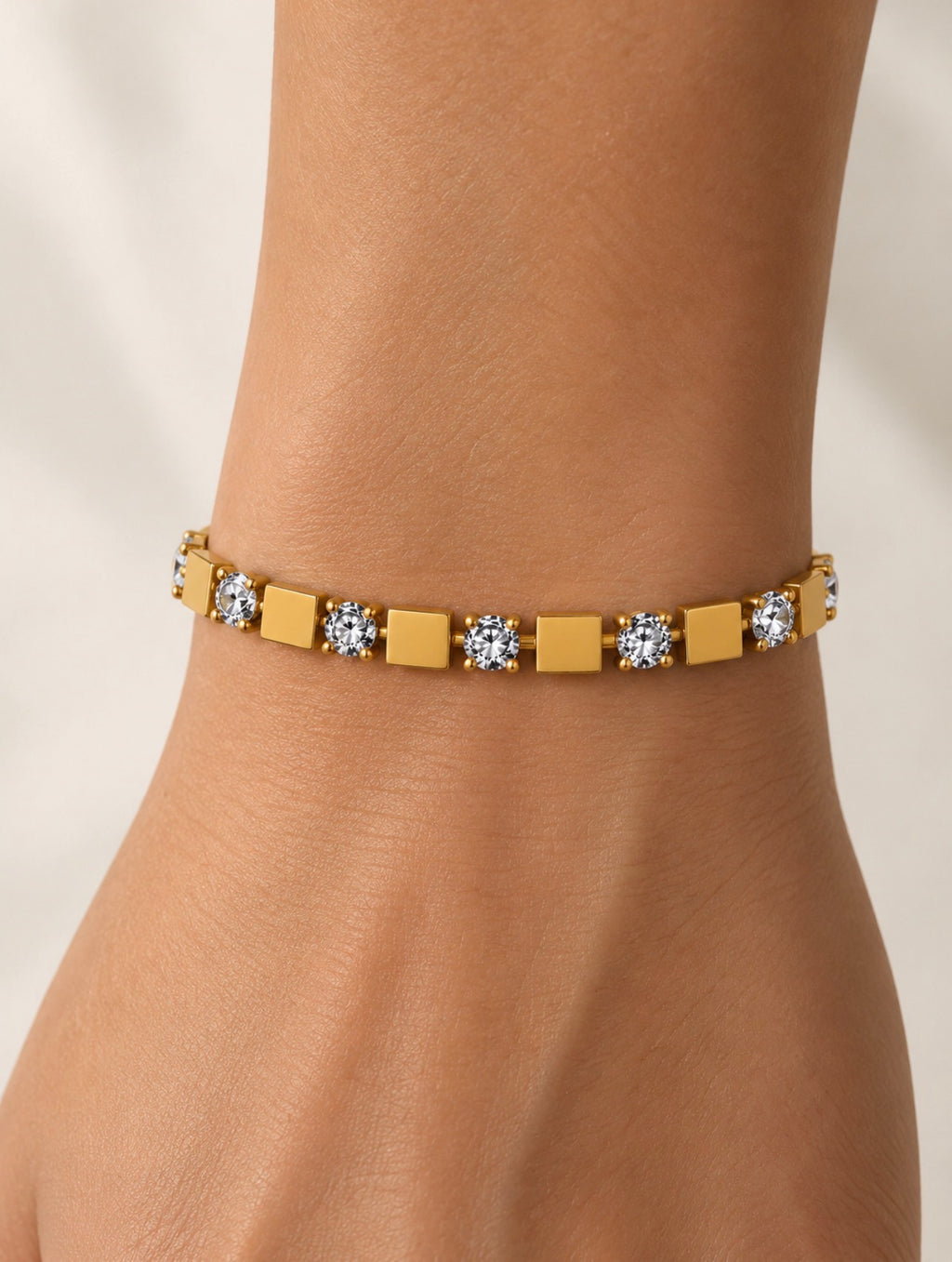 Détail d’un bracelet alternant carrés dorés et pierres claires