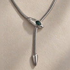 Détail d’un collier serpent argenté avec pierre verte