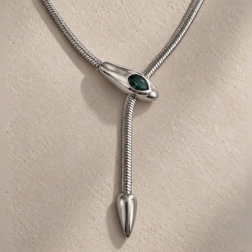 Détail d’un collier serpent argenté avec pierre verte