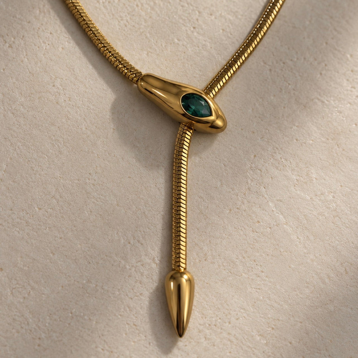 Détail d’un collier serpent doré avec pierre verte