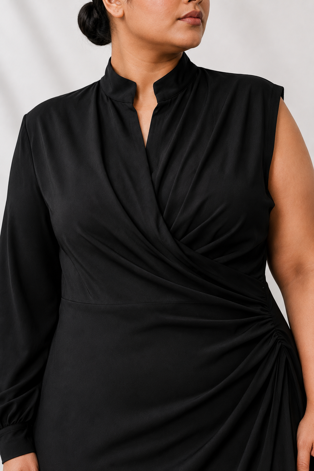 Détail du décolleté drapé d’une robe noire asymétrique