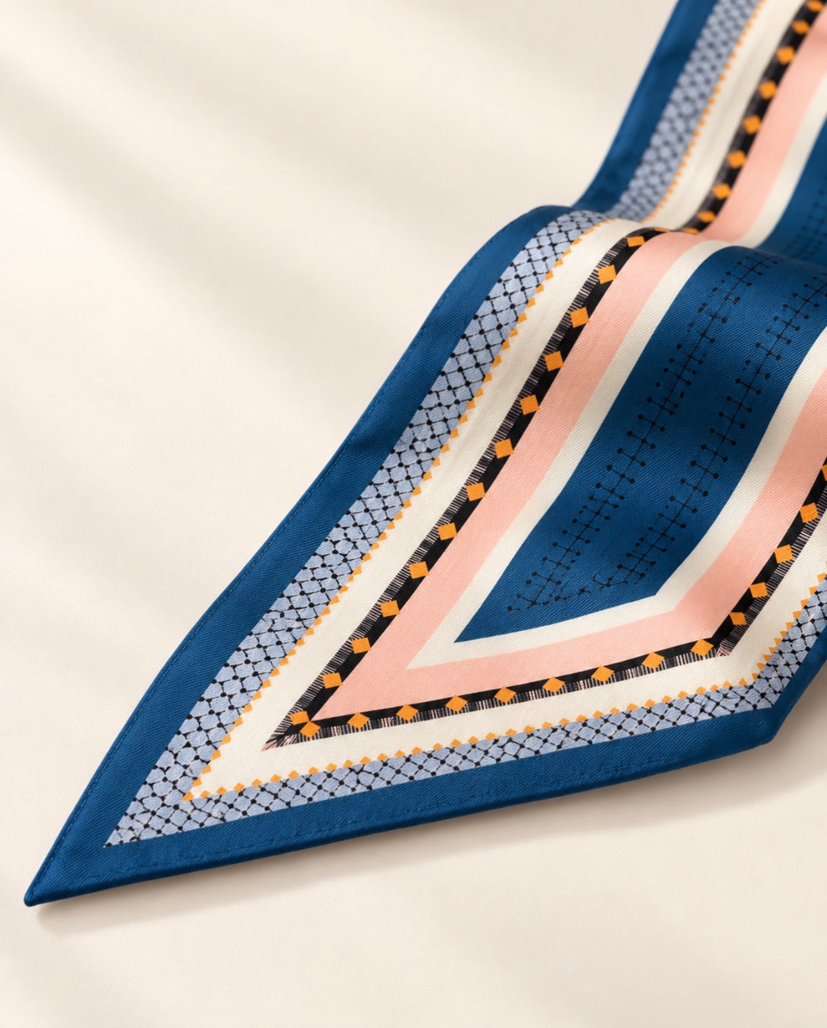 Détail de la pointe du foulard Rue Crémieux : bandes bleues, roses et ivoire et fines frises géométriques.
