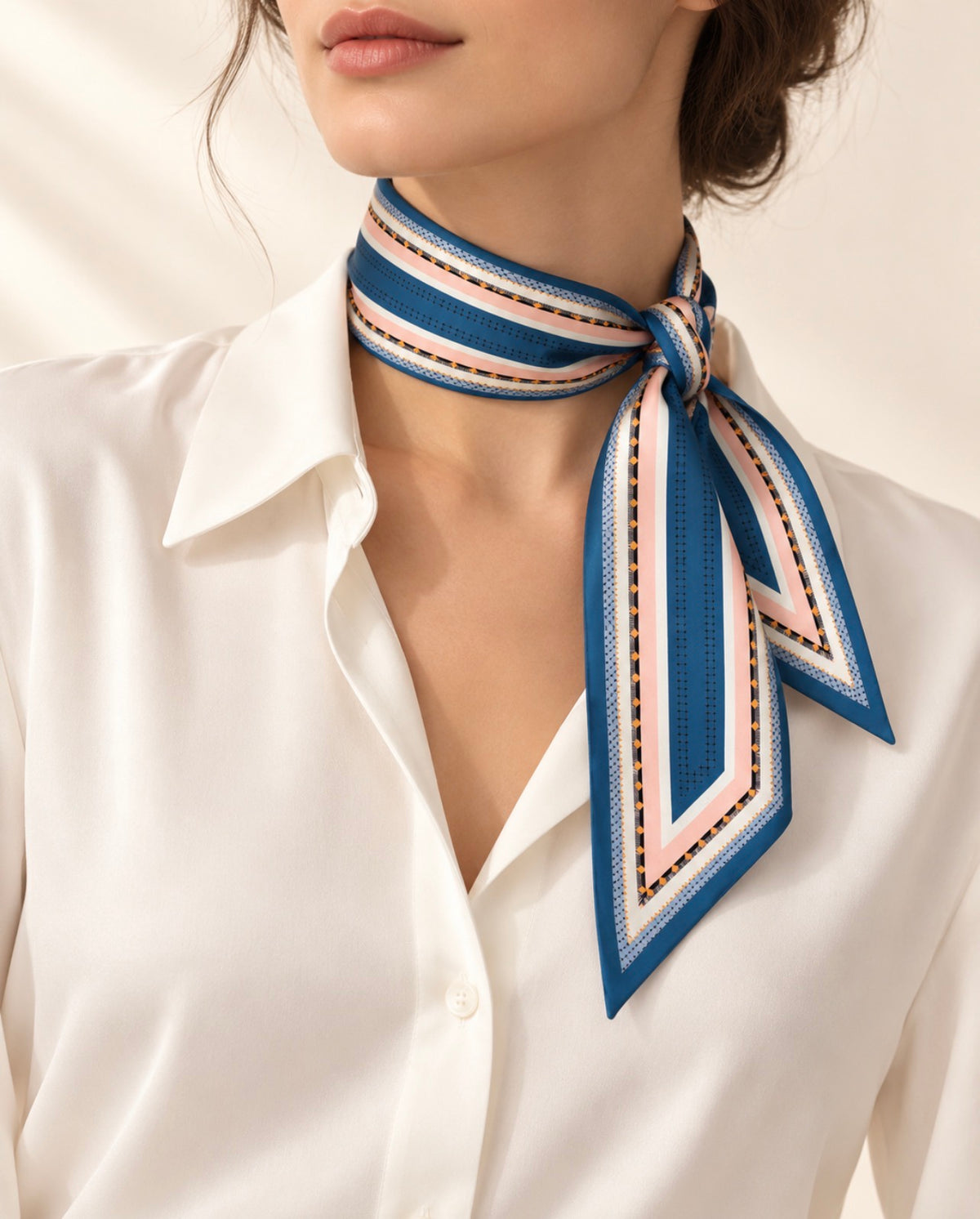 Foulard long Rue Crémieux en soie bleu et rose, noué sur le côté du cou avec une chemise blanche.