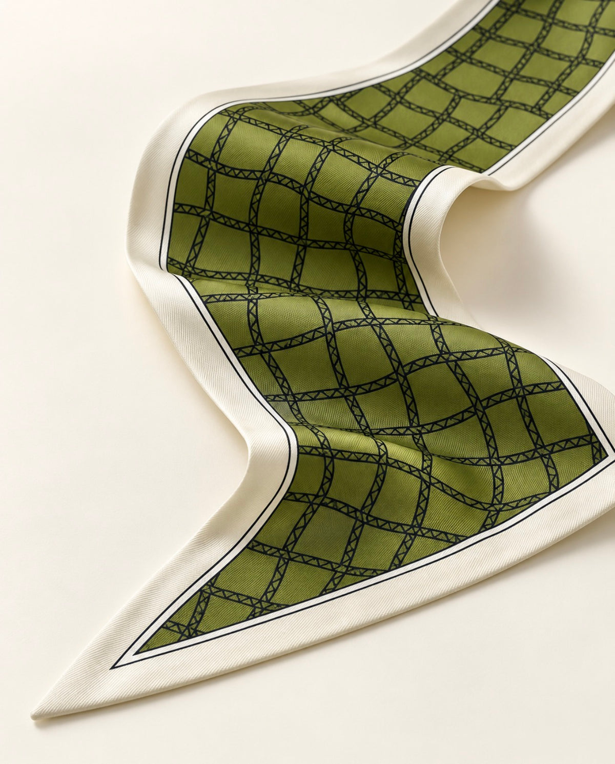 Détail du foulard Rue de Grenelle en soie : quadrillage noir sur fond vert olive, bordure ivoire soulignée d'un liseré noir.