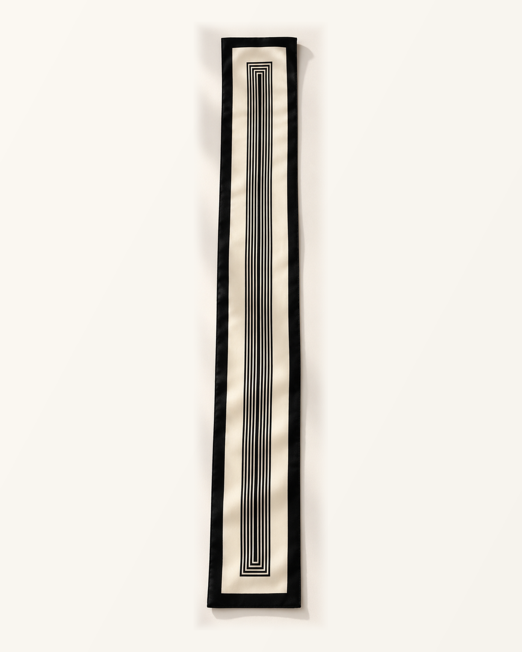 Foulard long Rue de l’Odéon déployé à plat, fond ivoire, bordure noire et motif central de rectangles concentriques noirs allongés.