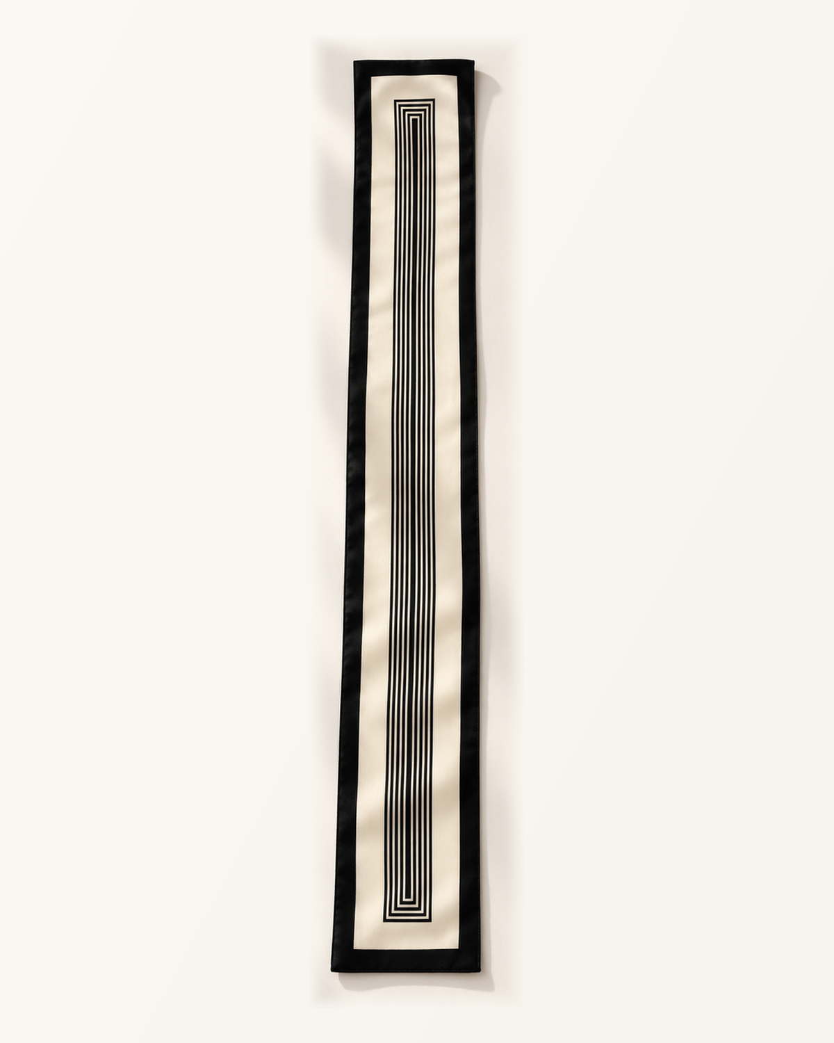 Foulard long Rue de l’Odéon déployé à plat, fond ivoire, bordure noire et motif central de rectangles concentriques noirs allongés.