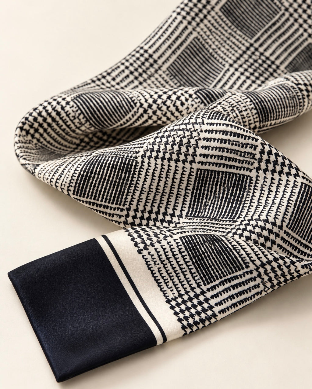 Zoom sur le foulard Rue de Verneuil en soie, motif de carreaux noir et ivoire, lignes entrecroisées et extrémité unie noire.