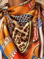 Gros plan du foulard Rue des Barres porté, avec motifs de sellerie, sangles, léopard et bordure bleue.