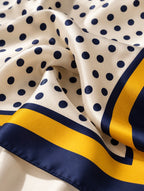 Détail du foulard Rue du Bac en soie : pois bleu marine sur fond ivoire et bordure jaune doré et marine.