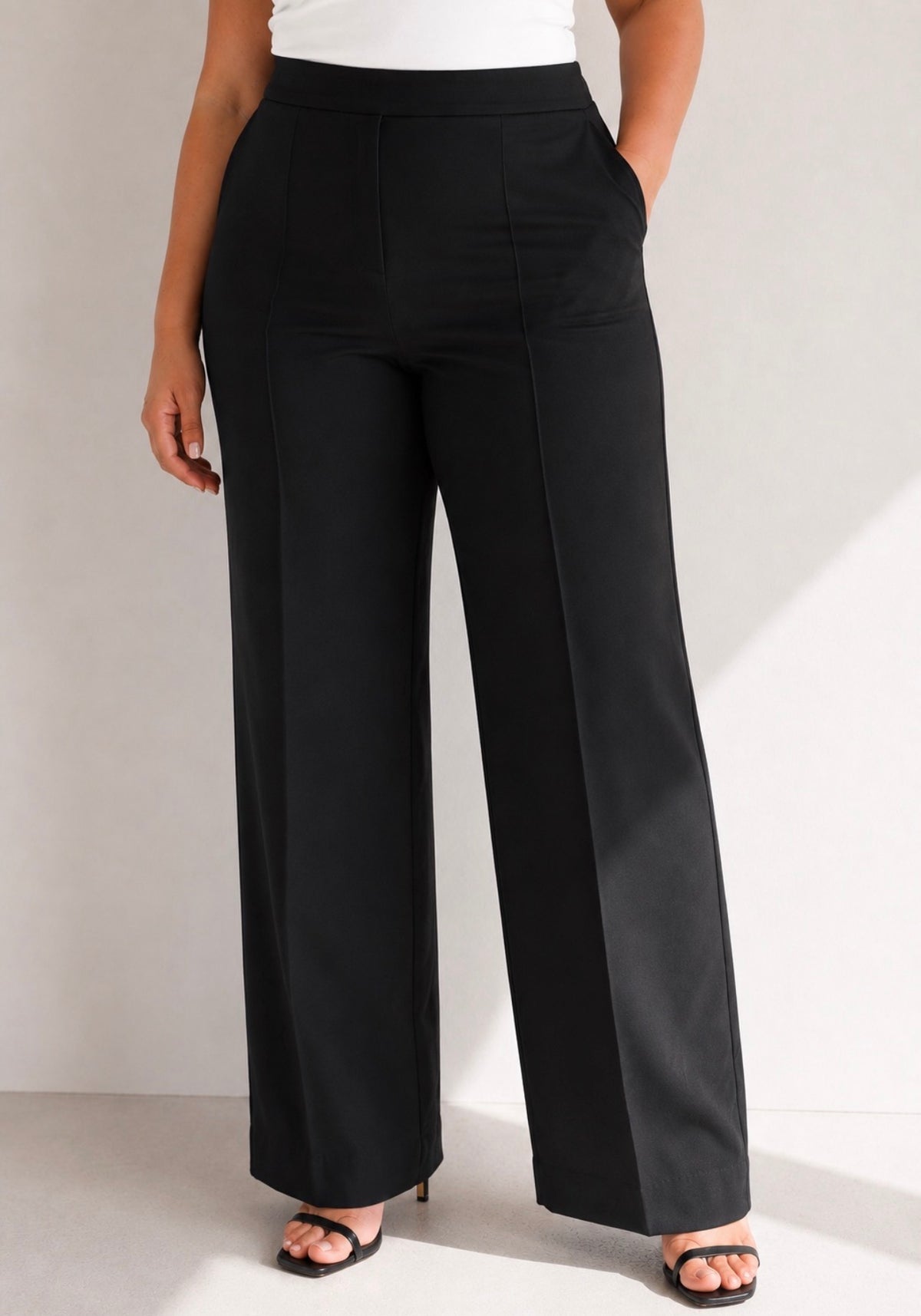 Pantalon noir à plis et jambes larges porté