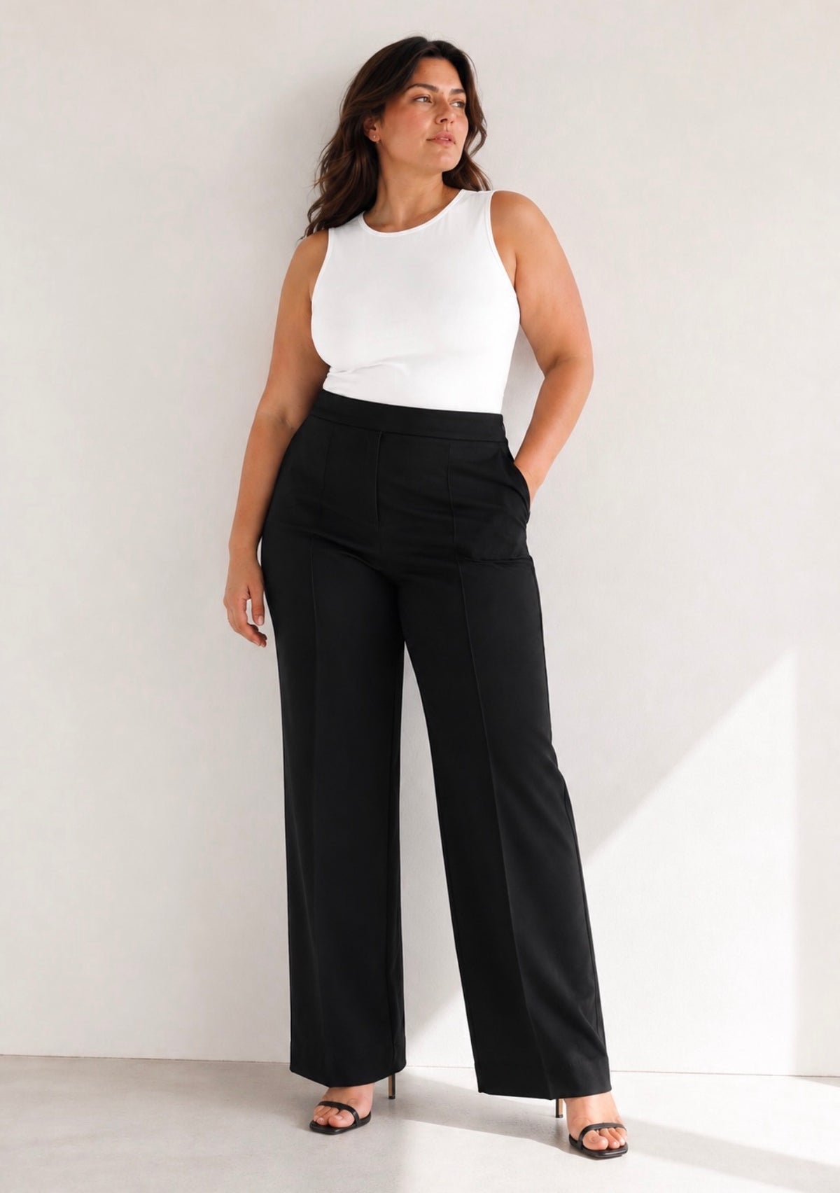 Pantalon noir ample porté dans un intérieur lumineux