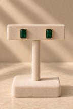 Petites boucles dorées à pierres vertes rectangulaires sur présentoir