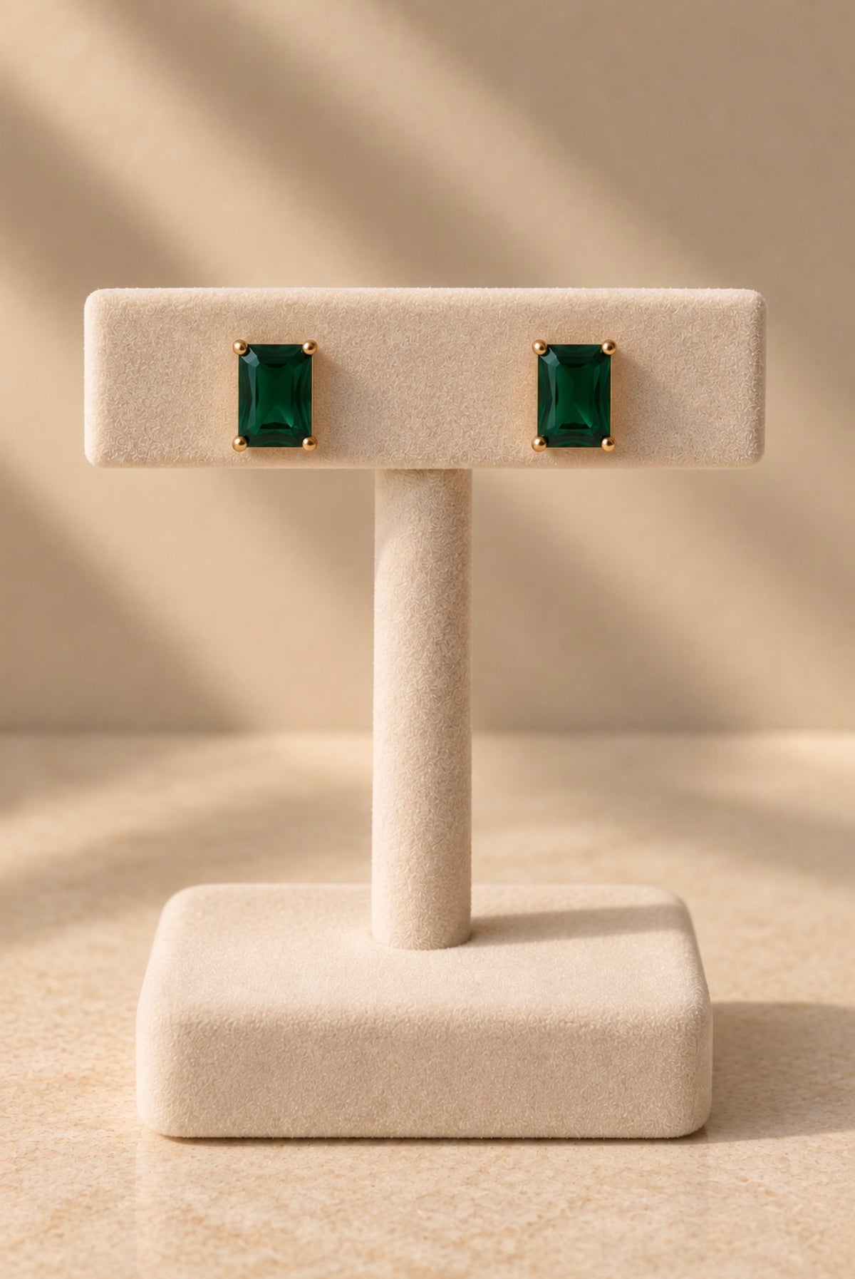 Petites boucles dorées à pierres vertes rectangulaires sur présentoir